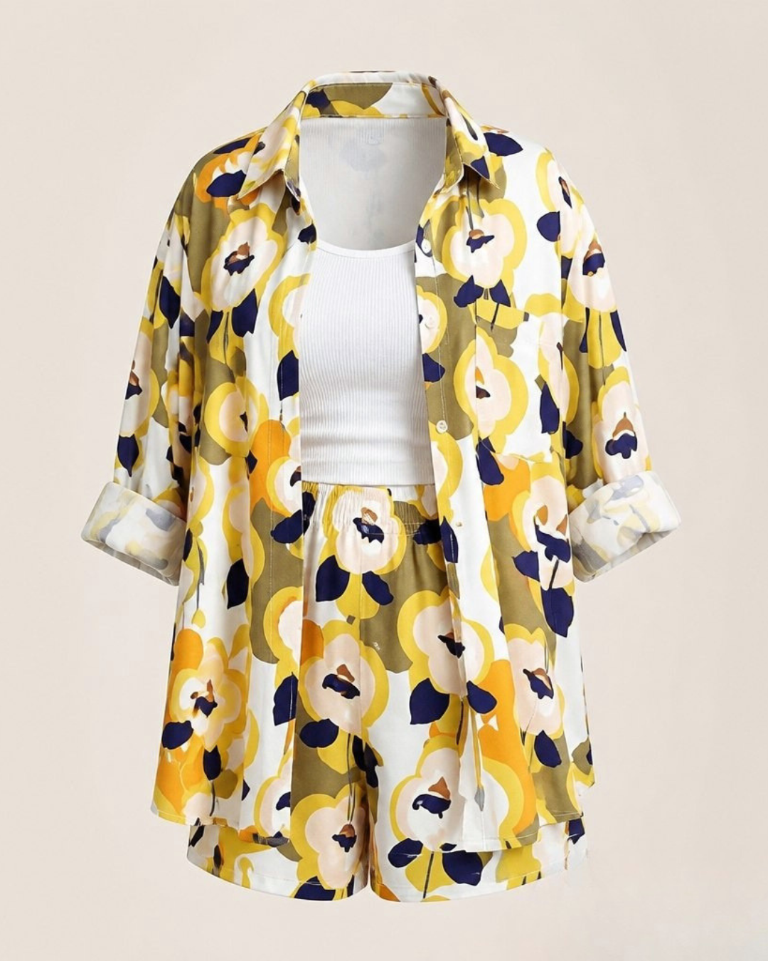 Yellow Viscose Shorts A women's two-piece matching set featuring a short-sleeve button-up shirt and shorts in a bold yellow, navy blue, and white floral pattern, styled over a white ribbed tank top on a mannequin against a solid beige background.