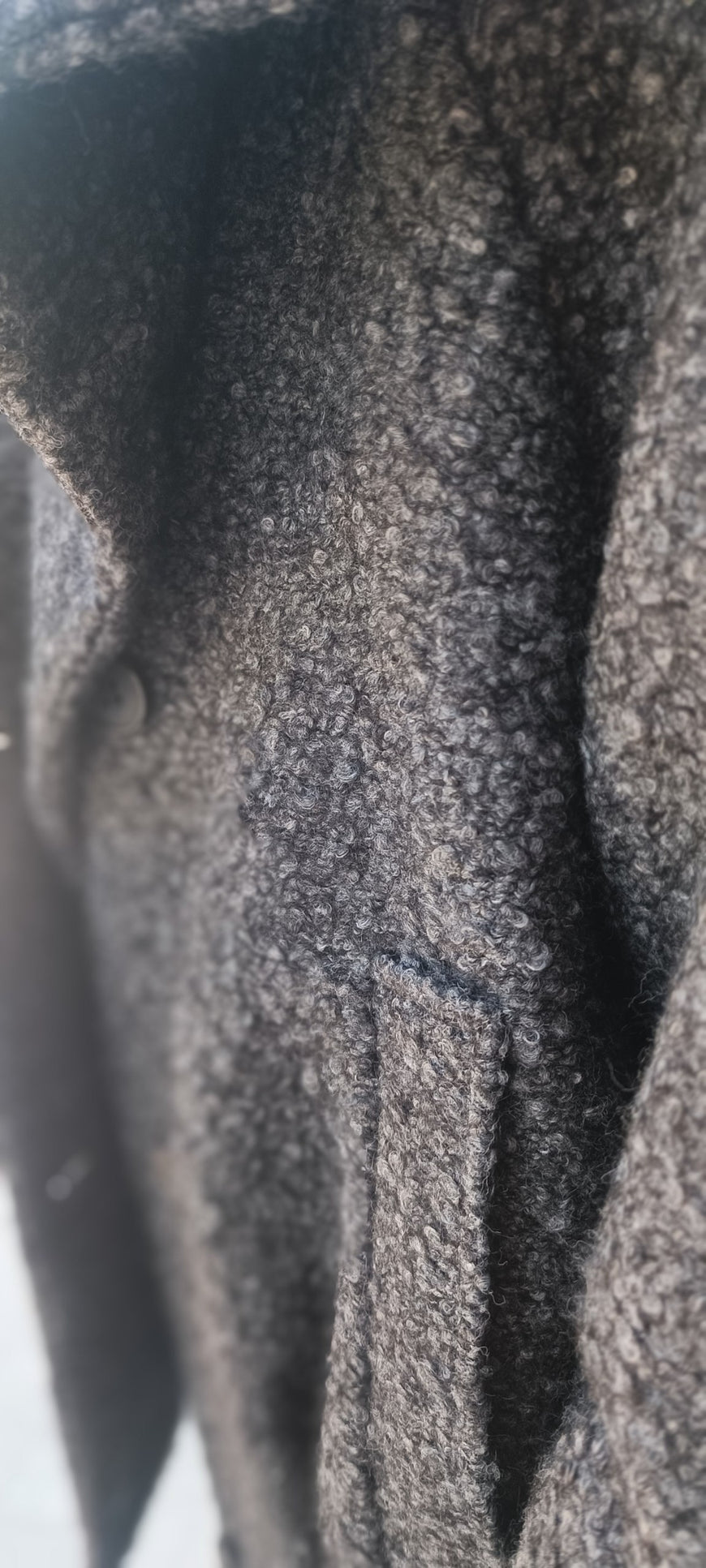 Close-up of a dark gray textured wool or fleece fabric surface with soft folds and a slightly fuzzy, heathered appearance.